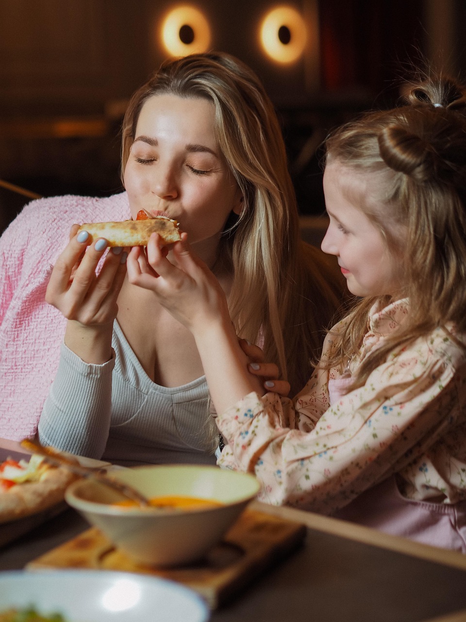 Mamma e figlia mangiano la pizza